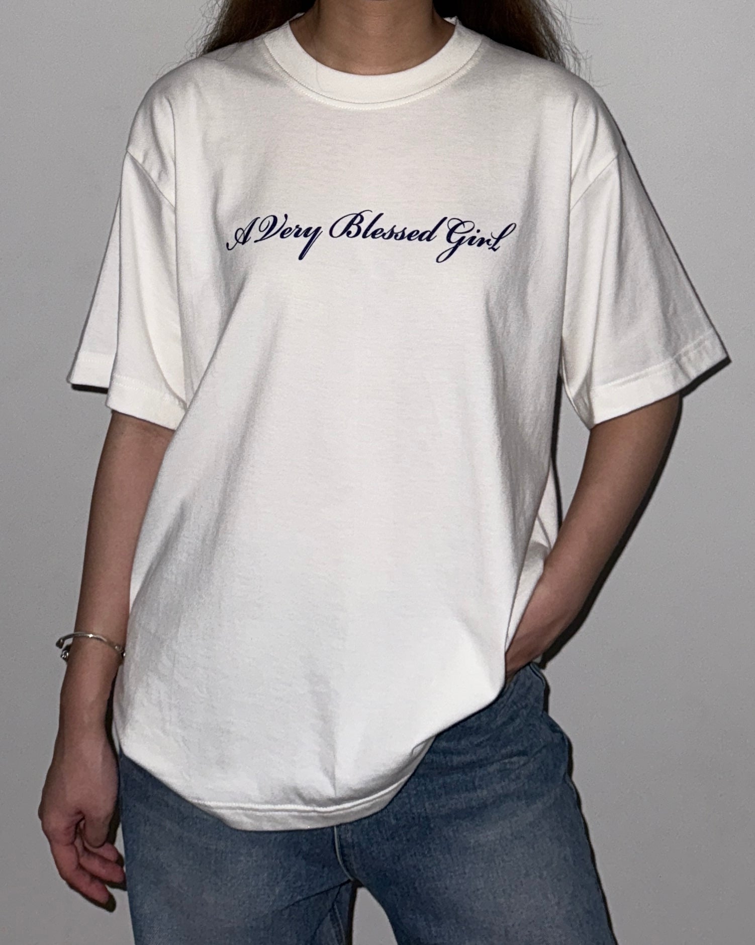 Person wearing a white t-shirt with 'A Very Blessed Girl' text on a plain background