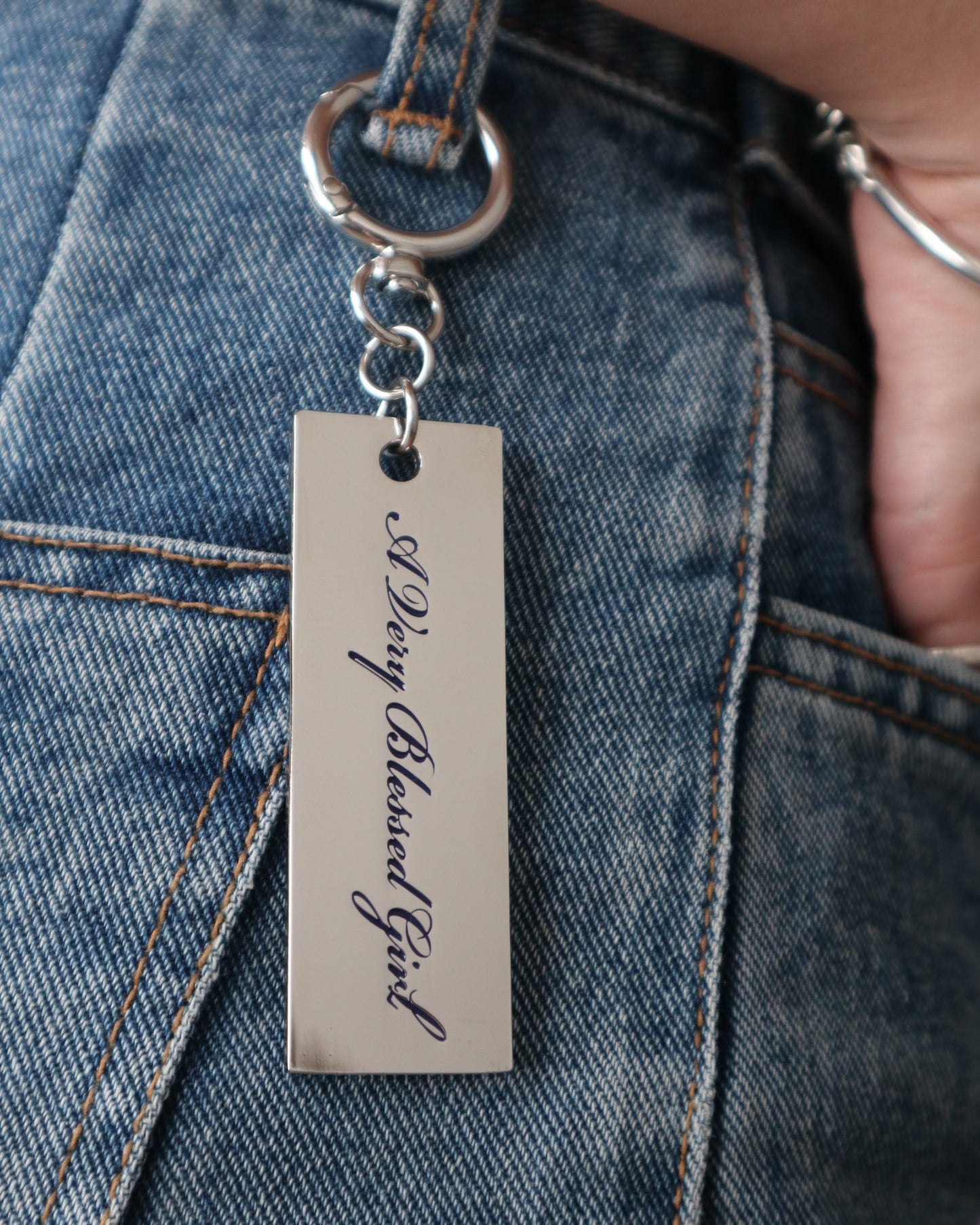 Metal keychain with engraved text on a denim jeans belt loop