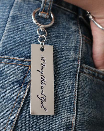 Metal keychain with engraved text on a denim jeans belt loop
