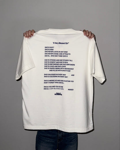 White t-shirt with text held by a person against a gray background